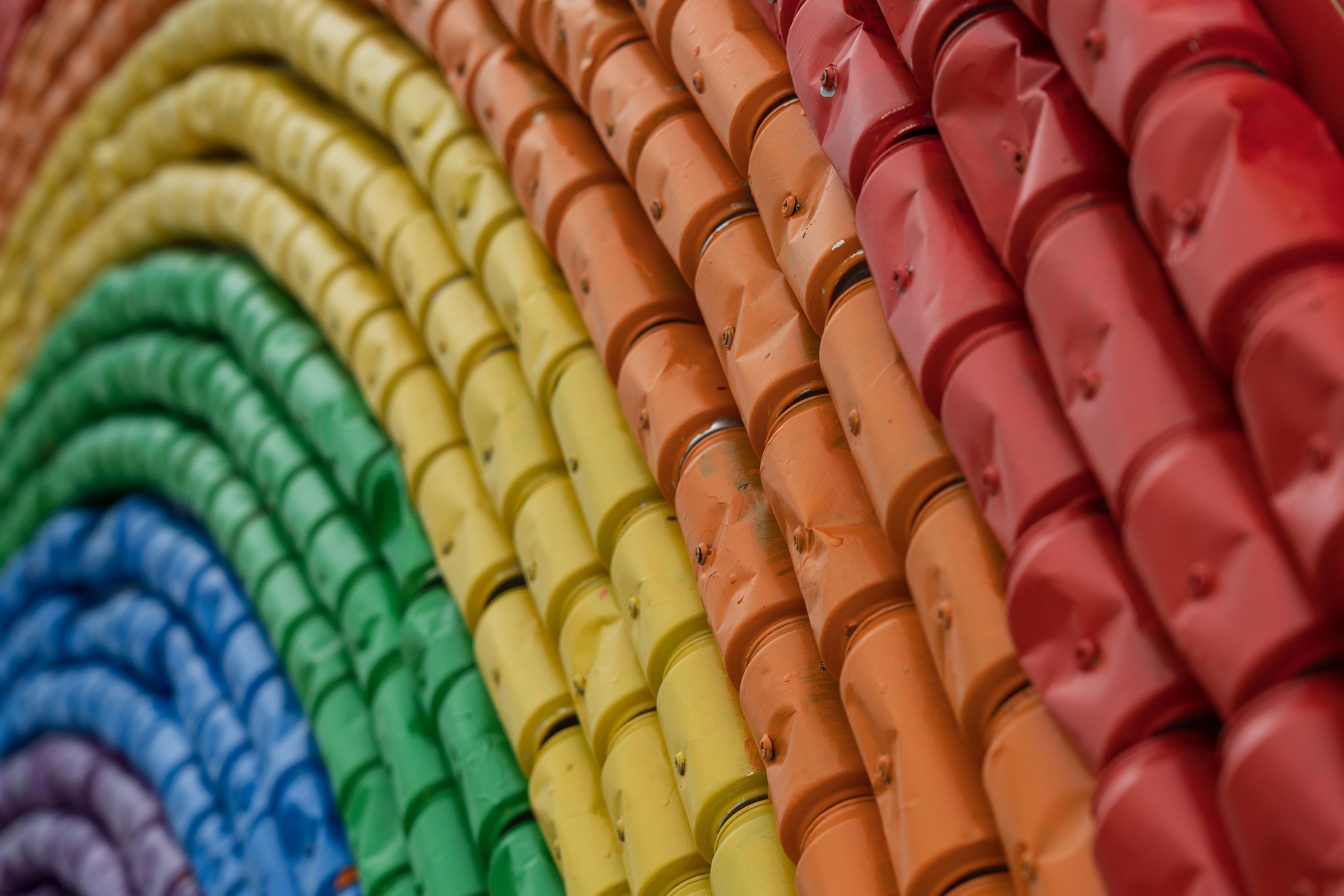 A close-up of painted aluminium cans, colored like a rainbow