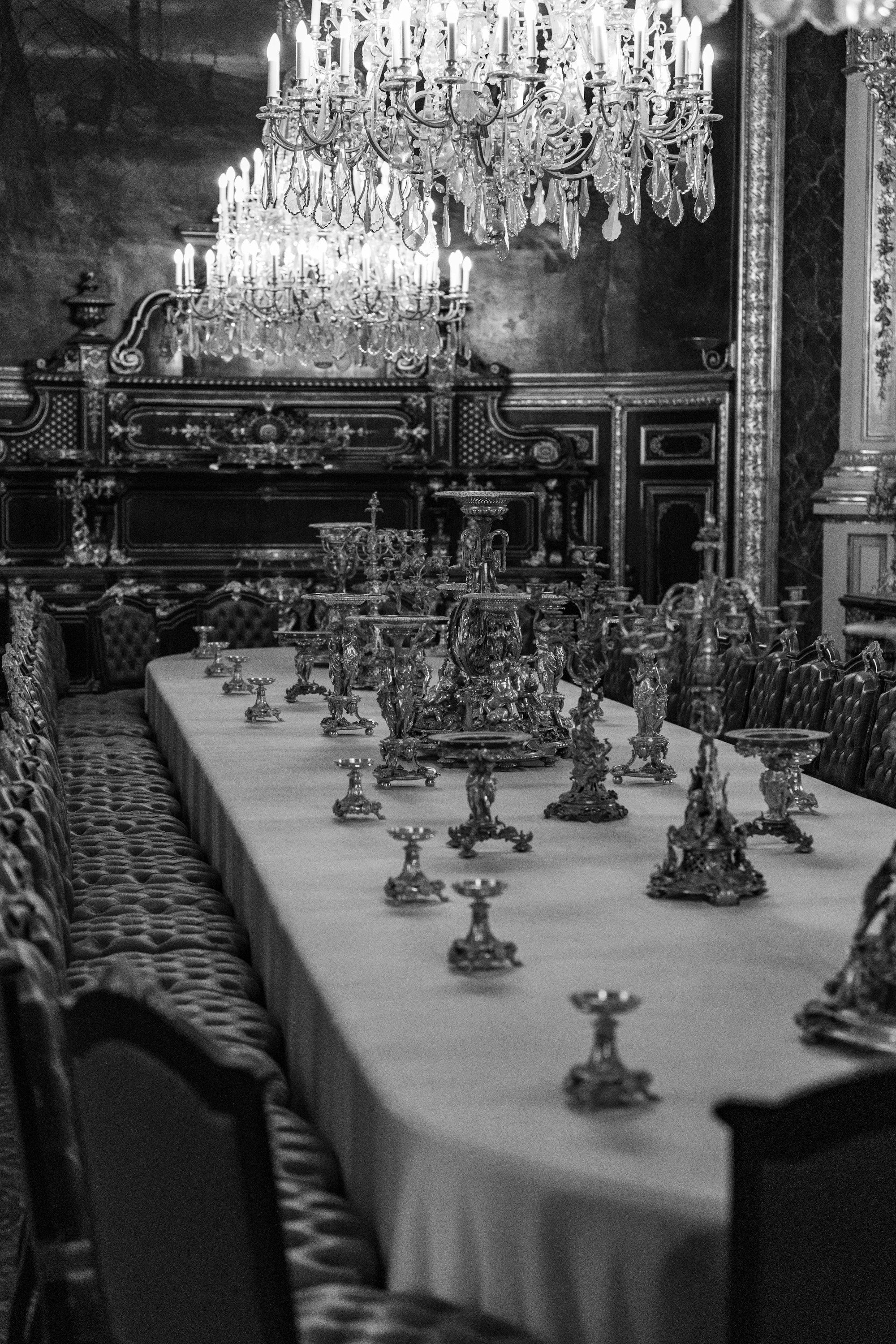Ornate silver candelabras on a long dining table beneath a crystal chandelier